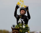 Jockey Juan Hernandez smiles while holding a winning garland atop his racehorse Bacio.