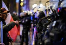 Protester facing riot police stationed in front of the Constitutional Tribunal building in Warsaw.