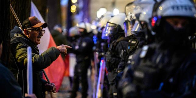 Protester facing riot police stationed in front of the Constitutional Tribunal building in Warsaw.