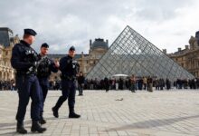 French riot police officers patrolling near the glass Pyramid of the Louvre Museum in Paris.