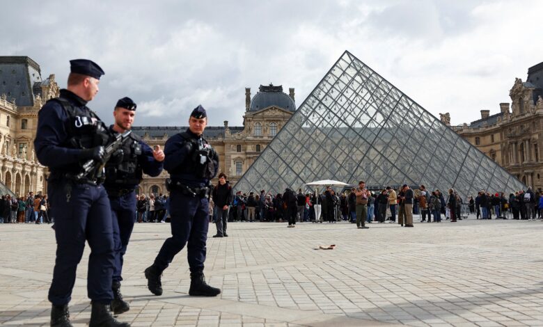 French riot police officers patrolling near the glass Pyramid of the Louvre Museum in Paris.